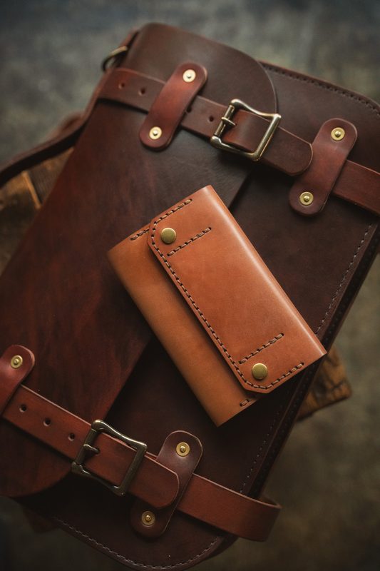Shell cordovan ledger wallet strapped onto a dark harness leather case