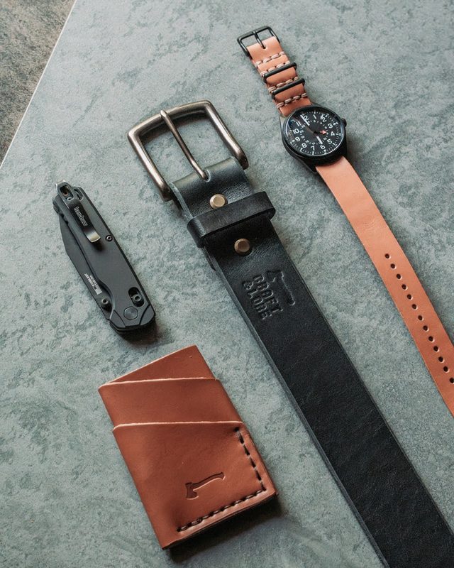 Black leather belt, card wallet, watch and knife on gray stone
