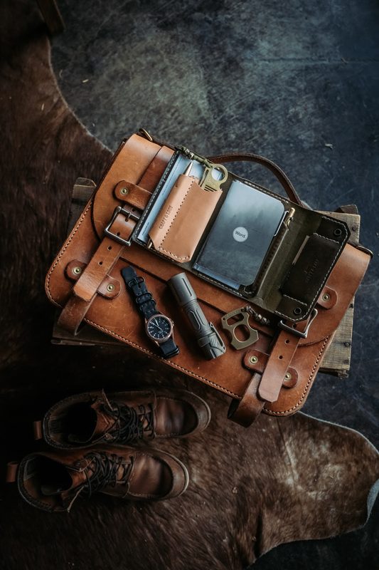 Open leather checkbook wallet with a watch, flashlight and keys on hide