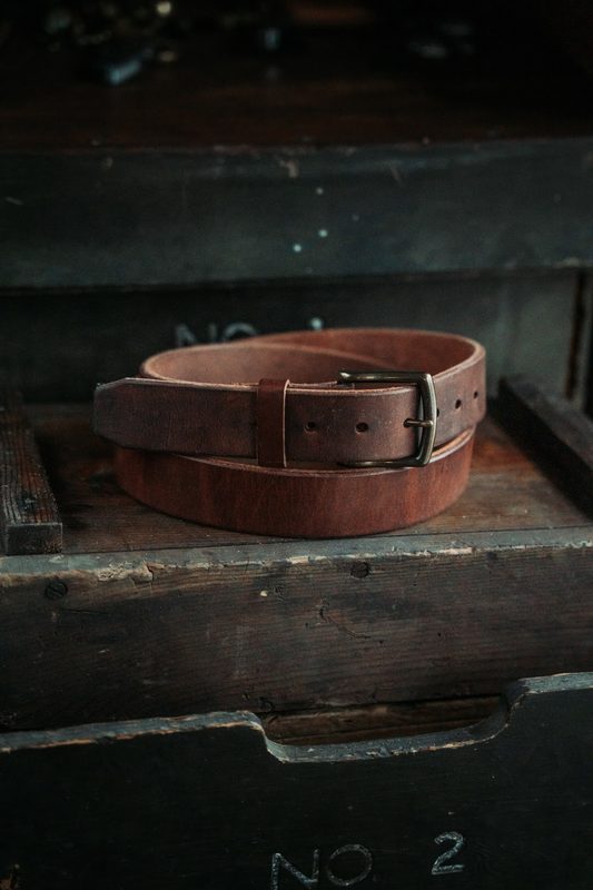 Dark brown leather belt coiled on an old wooden crate