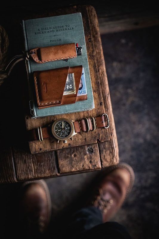 Leather wallet, comb and watch on a book, boots below