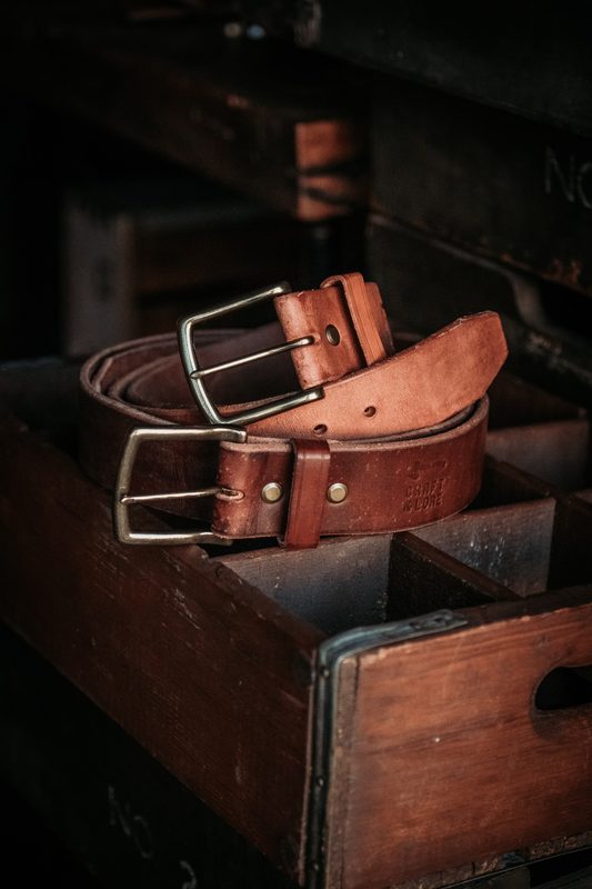 Brown leather belts coiled in a wooden drawer
