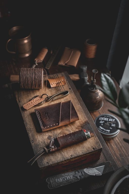 Leather wallets and tools on a dark workshop table