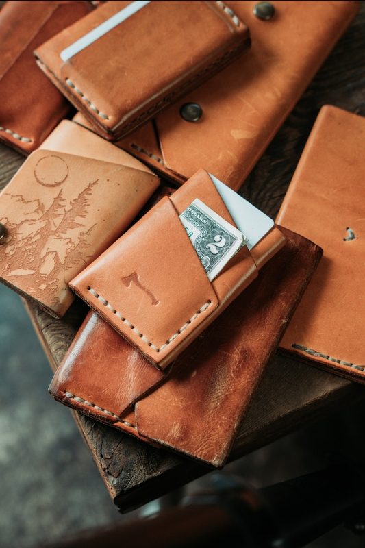 Stack of tan leather wallets with tooled and stamped designs