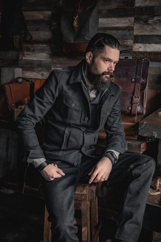 Man in black workwear seated in a workshop