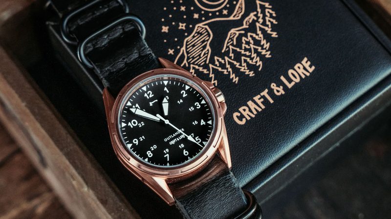 Bronze watch on a black NATO strap over an embossed Craft & Lore box