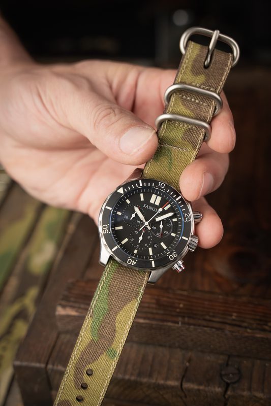 Hand holding a chronograph on a camo hybrid strap
