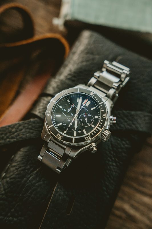 Steel chronograph on a bracelet resting on a leather roll pack