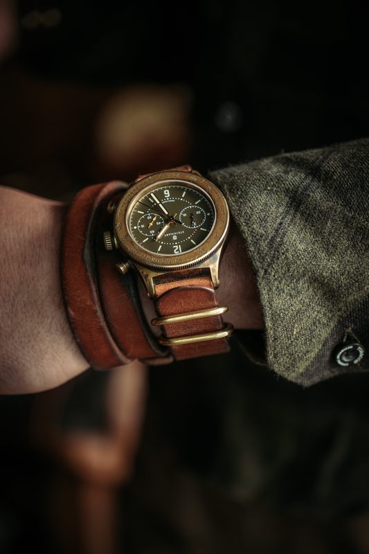 Brass field watch on a layered leather strap on the wrist