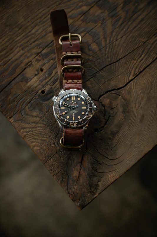 Dive watch on a brown leather NATO strap on a split log
