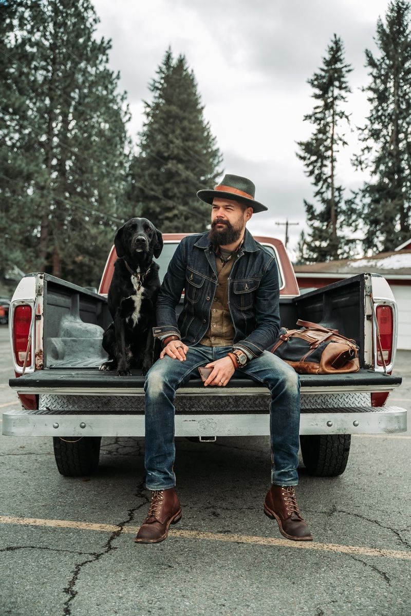 Chad sitting on the tailgate of a vintage pickup with his black dog