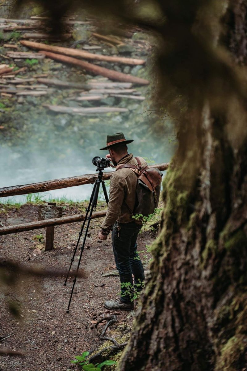 Chad at a tripod photographing a misty waterfall through old growth trees